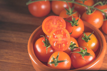 tomates cherry en rama recien recogidos en mader y vasija de barro