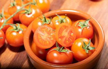 tomates cherry en rama recien recogidos en mader y vasija de barro