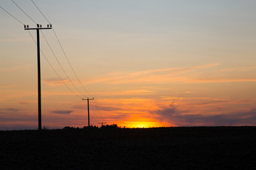 Colorful sunset with power poles leading to the horizon