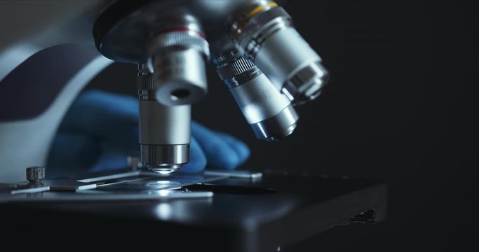 Crop closeup shot of microscope in the laboratory, scientist is conducting study examines the sample on a slide