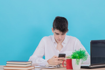 teenage student sitting at the desk with mobile phone