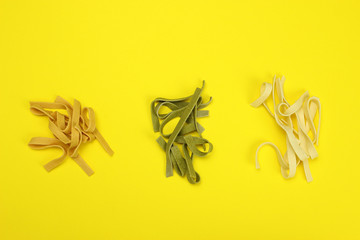 Colored uncooked noodles, macaroni close -up on a yellow background