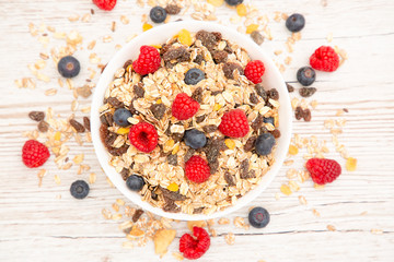 Breakfast Served in the morning with corn flakes Whole grains and raisins with milk in cups and Strawberry, Blueberry, Raspberry, Kiwi on the wood table,Diet food or healthy food in the morning.