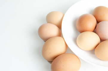 fresh brown eggs on a white plate in a deep plate