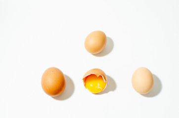 a group of fresh brown chicken eggs on a white background and one broken
