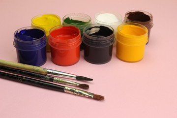 Gouache cans on a pink background with tassels