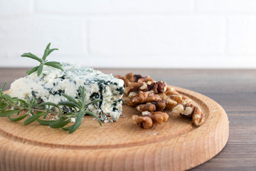 Obraz na płótnie Canvas Blue cheese on a wooden serving board with walnuts