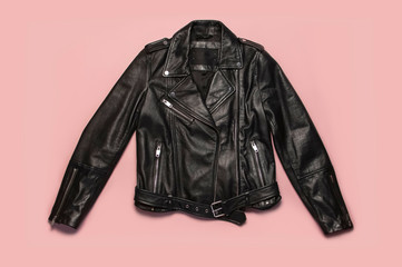 Black women's leather jacket on pink background top view. Fashionable modern trendy women's...