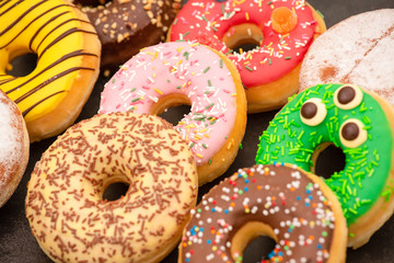 Dessert, Donuts, chocolate and strawberry circles, sugar and cream on Donuts and hot coffee cups, preparation for a break or party on the wooden table background.