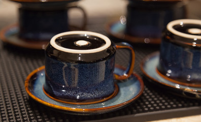 Clean dried hygienic vintage coffee drinking cups placed upside down on earthenware saucers, ready to use. Liquid serving containers used in Food and Drink Catering Service Industry, Utensils concept.