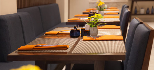 Selective Focused Empty Indoor Dining Tables, Place Mats, Cutlery and Napkin Setting. Dining Venue, Food Catering Service, Restaurant Table Decoration and Architecture Interior Design concept