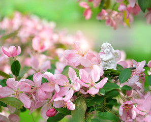 angel and Spring flowers in garden. White Cupid and Pink cherry. Springtime, romantic scene. concept for Easter holiday, mothers day. 