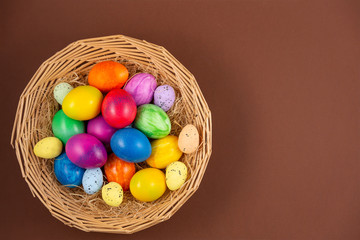 Fototapeta na wymiar Beautiful group Easter eggs in the spring of easter day, red eggs, blue, purple and yellow in Wooden basket on the brown background