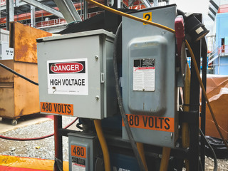 High voltage panel on the field with danger sign.