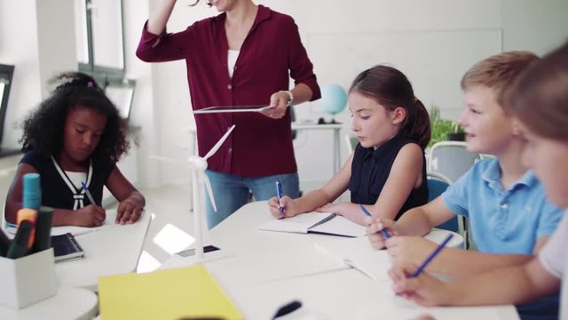 A group of small school kids with teacher in class learning about environment.