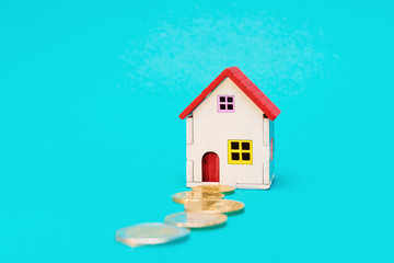 House toy with Euro coins path over blue background. Mortgage and rent concept