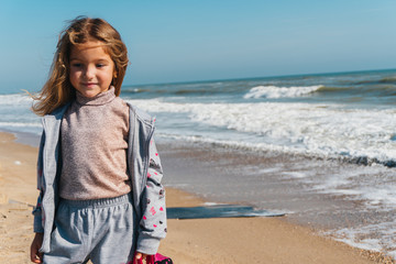 Little girl on the sandy shore of the ocean