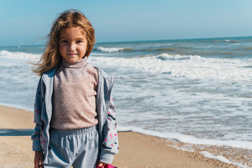 Little girl on the sandy shore of the ocean
