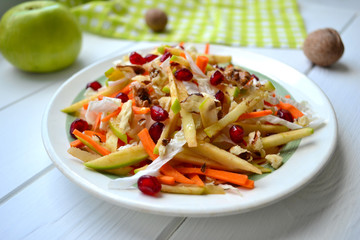Healthy salad with cabbage, apples, carrots, nuts and pomegranate seeds.