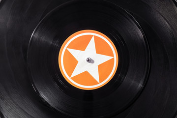 Black vinyl record on DJ turntable. Black vinyl background with white and orange star screen in...