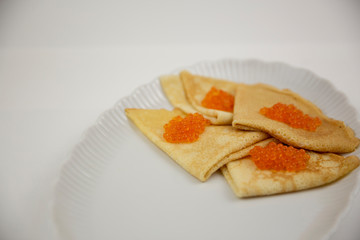 caviar with pancakes on a white plate in general terms