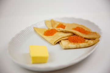 caviar with pancakes on a white plate and butter