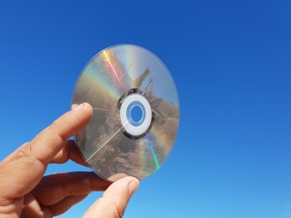 cd in hand in a blue sky background