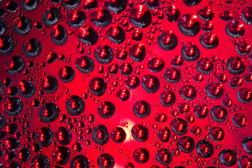 Drops of water on the glass surface with reflections of bright color spots.