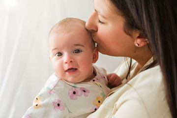 family mother playing with newborn baby on the baby room