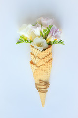 bouquet of delicate flowers in a waffle Cup for ice cream on a white background, top view, large, summer and spring minimalism