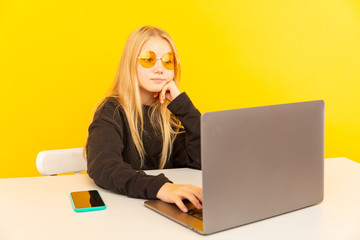 Cute blond girl at home in front of laptop making video for vlog and working as blogger, recording video tutorial for Internet
