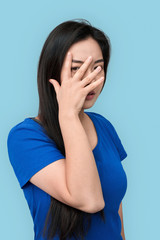 Freestyle. Chinese woman standing isolated on grey covering face hiding personality