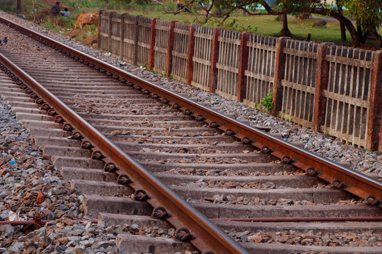 Landscape of railroad tracks in India cutting across rural countryside, Typical scene with litter thrown around