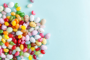 Happy Easter concept. Preparation for holiday. Easter candy chocolate eggs and jellybean sweets isolated on trendy pastel blue background. Simple minimalism flat lay top view copy space.