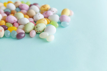 Happy Easter concept. Preparation for holiday. Easter candy chocolate eggs and jellybean sweets isolated on trendy pastel blue background. Simple minimalism flat lay top view copy space.