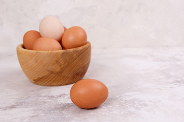 Rustic eggs in a wooden plate, one egg next to the plate.