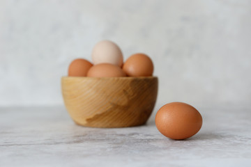 Rustic eggs in a wooden plate, one egg next to the plate.