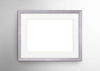 Fototapeta premium Empty frame. Blank light grey mounted landscape frame on white wall