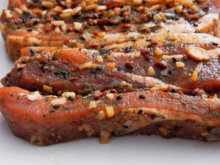 Raw uncooked pork belly portions in soy sauce marinade on a light grey surface.