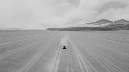 Black and white drone photo of car crossing the Bolivian desert 