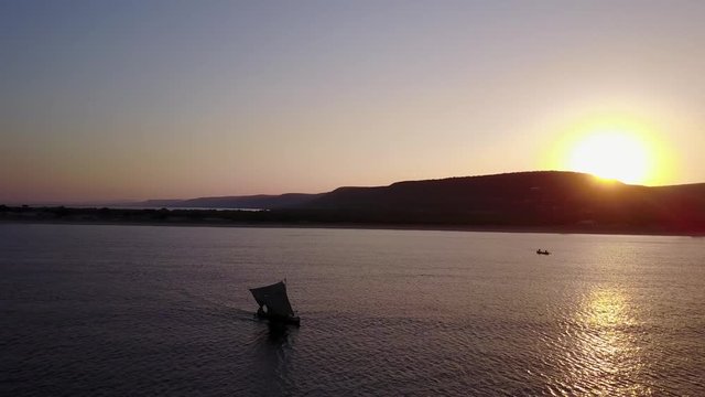 drone aerial footage of african fisherman on piroque/ small fisherboat sailing into sunset in southern madagacar/Anakao
