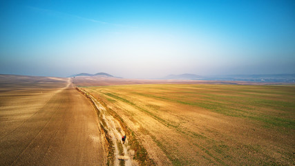 Fototapeta na wymiar Aerial view of ploughed agricultural field. Dirt road through arable land Panorama