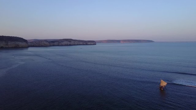 aerial drone top down of african fisherman on piroque/ small fisherboat sailing into sunset in Saint augustin in Madagascar