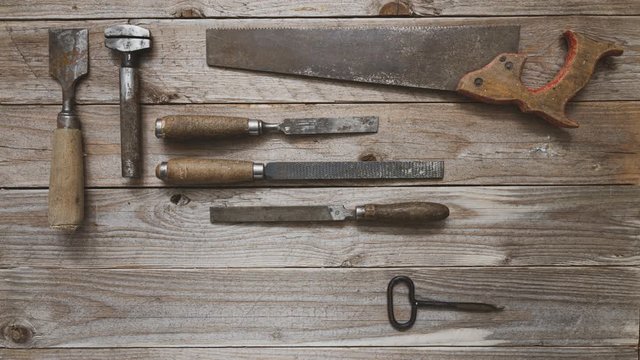 Vintage woodworking tools, hand drill, chisels, hand saw, plane, nail file and nails moving and leaving an opening for logo or text. Carpentry, diy, craftsmanship concept, flat lay 4k stop motion