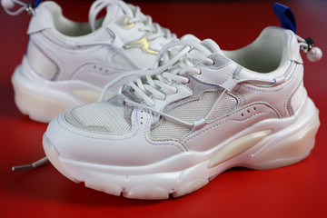 a pair of white women's sneakers on a red background