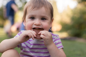 A toddler is enjoying a snack outside in the summer time.