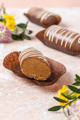 Chocolate pop cake with spring delicate flowers on a pink marble background.