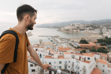 young male traveler stands on top of castle, city view, Peniscola Spain