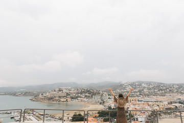 young female traveler stands on top of castle, city view, Peniscola Spain