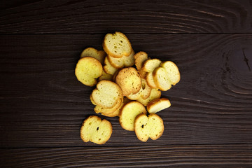 Bruschette chips, dry slices of baked bread, snacks scattered on wooden background, top view